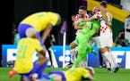 Croatia players embrace goalkeeper Dominik Livakovic after defeating Brazil in a World Cup quarterfinal soccer match.