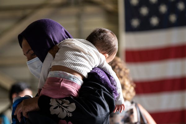 A woman holds a baby at the Sigonella NATO Airbase, Italy, Sept. 1, 2021. While a group of Afghan evacuees was boarding a plane headed to the US on We