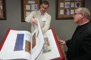 Mike Nordberg, a senior account executive at the John Roberts Co., shows the Rev. Erich Rutten of St. Odilia’s parish pages of the Heritage Edition 