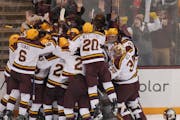 Gophers players celebrate Logan Cooley’s overtime goal on Sunday. 