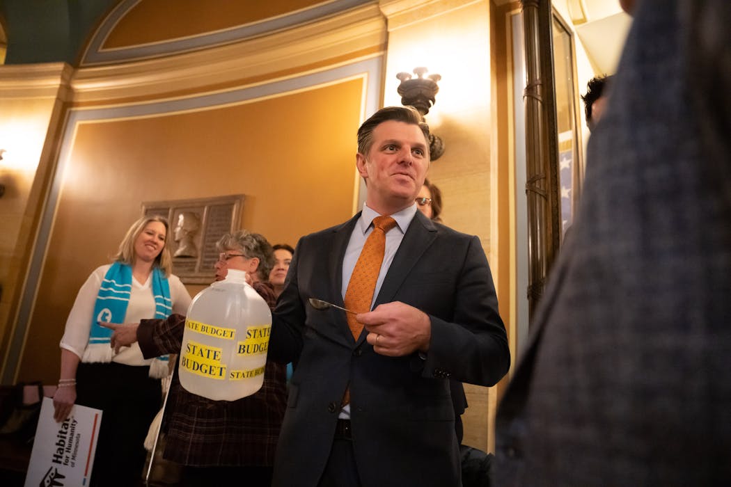 Rep. Michael Howard held a gallon of water and a spoon to illustrate that housing is only a small portion of the state budget. 