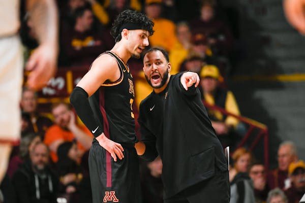 Minnesota head coach Ben Johnson, right, talks with forward Dawson Garcia during a break in action in the first half of an NCAA college basketball gam