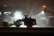 A front-end loader plows fresh snow as a Spirit Airlines plane is de-iced at Minneapolis-St. Paul International Airport Thursday. 