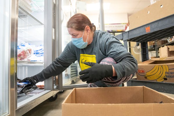 Dawn Williams, a volunteer, stocked a freezer with pork on Jan. 24, 2022, at the Southern Anoka Community Assistance Food Shelf in Columbia Heights.