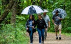 Alva Swenson, left, and friend Sue Strandberg, center, came prepared for a rain-soaked hike in September 2020 along Nine Mile Creek in Bloomington. Pa