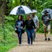 Alva Swenson, left, and friend Sue Strandberg, center, came prepared for a rain-soaked hike in September 2020 along Nine Mile Creek in Bloomington. Pa