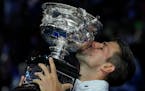 Novak Djokovic of Serbia kisses the Norman Brookes Challenge Cup after defeating Stefanos Tsitsipas of Greece in the men’s singles final at the Aust