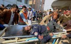 Workers and volunteers carry an injured victim of a suicide bombing upon arrival at a hospital in Peshawar, Pakistan, Monday, Jan. 30, 2023. 