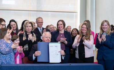 Surrounded by DFL legislators, Minnesota Gov. Tim Walz signs a bill to add a “fundamental right” to abortion access into state law Tuesday in St. 