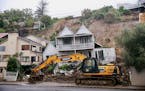 An excavator works at a home badly damaged by flooding and landslides in Auckland, New Zealand, Sunday, Jan. 29, 2023. New Zealand’s Northland regio