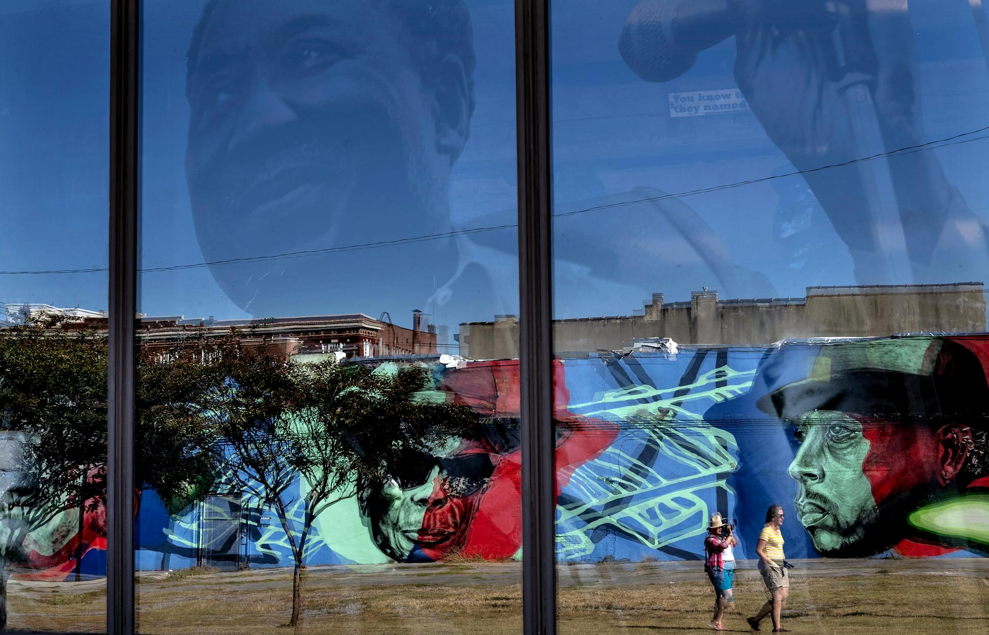 <b>Above:</b> Tourists walked by images of blues icons in Clarksdale: John Lee Hooker on a mural and Muddy Waters on a window of the Delta Blues Museum.<br><b>Below:</b> Jimmy “Duck” Holmes opened the door to the Blue Front Cafe, the area's oldest surviving juke joint, which his parents opened in Bentonia in 1948 to feed sharecroppers.
