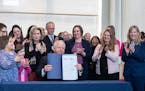 Surrounded by DFL legislators, Gov. Tim Walz signs a bill to add a “fundamental right” to abortion access into state law on Tuesday in St. Paul.