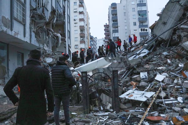 People and rescue teams try to reach trapped residents inside collapsed buildings Monday in Adana, Turkey.