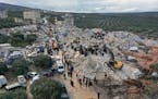 Civil defense workers and residents search through the rubble of collapsed buildings in the town of Harem near the Turkish border, Idlib province, Syr