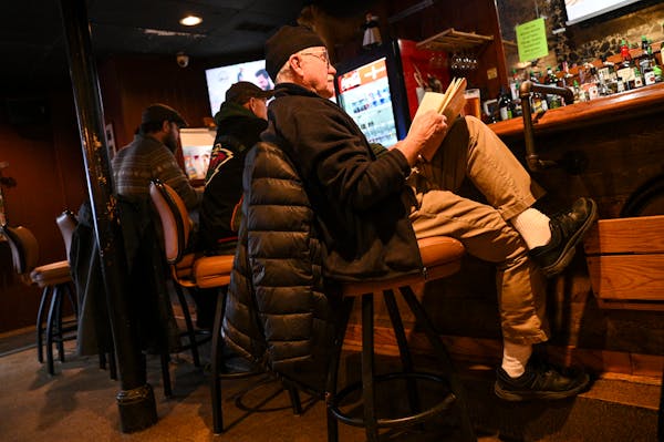 Jeff Hohman of Buffalo City, Wis., reads a short story at the bar during a commercial break in the Minnesota Wild game he was watching.