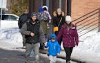 A couple escorts a child from a daycare centre after a city bus crashed into the facility in Laval, Quebec, Wednesday, Feb.8, 2023. At least eight peo