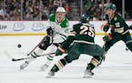 Dallas Stars left wing Mason Marchment (27), left, passes the puck while defended by Minnesota Wild defenseman Jonas Brodin (25), middle, and left win