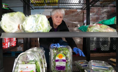Volunteer Deb Gallagher fills the shelves of the cooler at Open Door Pantry in Eagan on Wednesday. More Minnesotans visited food shelves in 2022 than 
