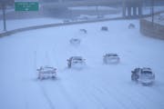 Snow-covered vehicles blend in with snow-blanketed Interstate 35W northbound near the Interstate 94 exchange Thursday in Minneapolis.