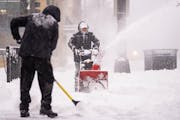 Luis Cabrera and Carlos Toro, left to right, cleared snow on the sidewalk in front of the Butcher’s Tale Feb. 23, 2023, in Minneapolis. More snow is