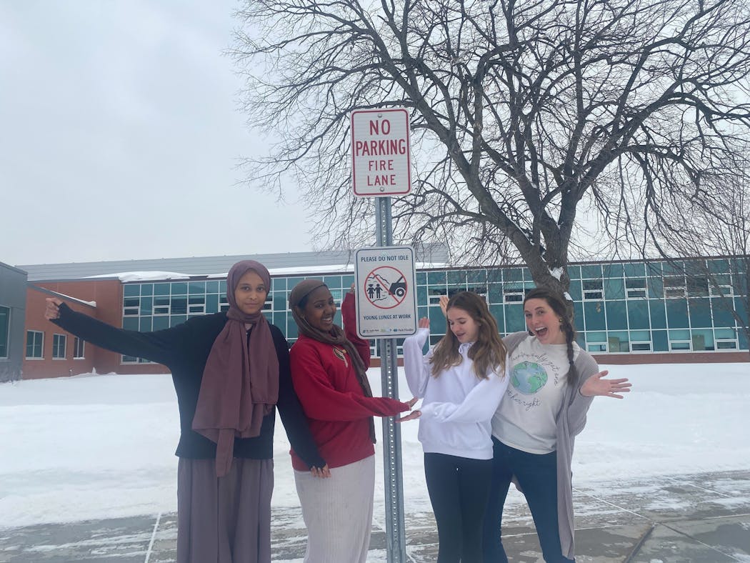 Students Suwaydah Aden, Ibtisam Ahmed, Erin Enright and their science teacher, Mehgan Setten, pose in front of one of the “Idle Free SLP” signs outside of St. Louis Park Middle School.