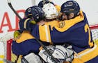 Mahtomedi forward Charles Drage (11) and defenseman Cavanaugh Bruner (2) celebrate the win with goaltender Charles Brandt (30) as time expires at the 