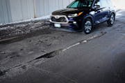A vehicle navigates a battered up, pothole laden stretch of 10th Ave. SE Tuesday, March 14, 2023 in Minneapolis, Minn. Temporarily patching streets is