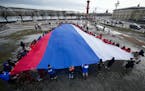 Young people unfurl a giant Russian flag during an action to mark the ninth anniversary of the Crimea annexation from Ukraine in St. Petersburg, Russi