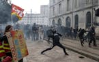 A protester throws a stone as he scuffle with riot police during rally in Nantes, western France, Thursday, march 23, 2023. French unions are holding 