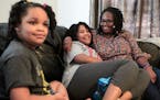 FILE - Deleah Payne, 12, center, spends time with her mother Delisa, right, and 6-year-old sister Delynn, left, as they watch movie clips on their liv