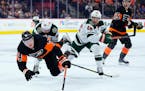 The Flyers’ Owen Tippett went sprawling after colliding with the Wild’s Frederick Gaudreau (89) and Jared Spurgeon (46) during the second period T