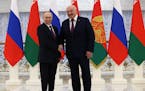 Russian President Vladimir Putin, left, and Belarusian President Alexander Lukashenko shake hands before their meeting at the Palace of Independence i