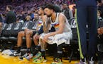 Minnesota Timberwolves forward Kyle Anderson, left, sits on the bench with guard Austin Rivers during the second half of an NBA basketball game agains