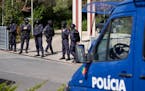 Police officers stand at the entrance of an Ismaili Muslim center in Lisbon, Portugal, Tuesday, March 28, 2023. Portuguese police have shot a man susp