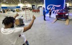 Cameron Briscoe of Minneapolis helps direct a Ford Mustang convertible onto a platform during setup for The Twin Cities Auto Show Thursday, March 30, 