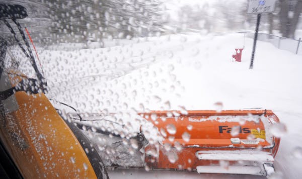 Jesse Rix, a public service worker with the St. Louis Park streets department, uses the wing plow of a snow plow to clear local roadways as snow conti