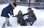 Neighbors Patti Frasher, left, and Lou Clark, right, pull NancyGrace Norman, middle, out of the snow after creating a snow angel in the deep pile of s