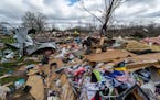 People walk through damage from a late-night tornado in Sullivan, Ind., April 1, 2023. 