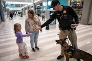 Lt. Kenny McDonough handed a trading card of his explosive-sniffing dog Ellie to Charlotte Conlin, 6, and her mother, Jaclyn, while he was on patrol a