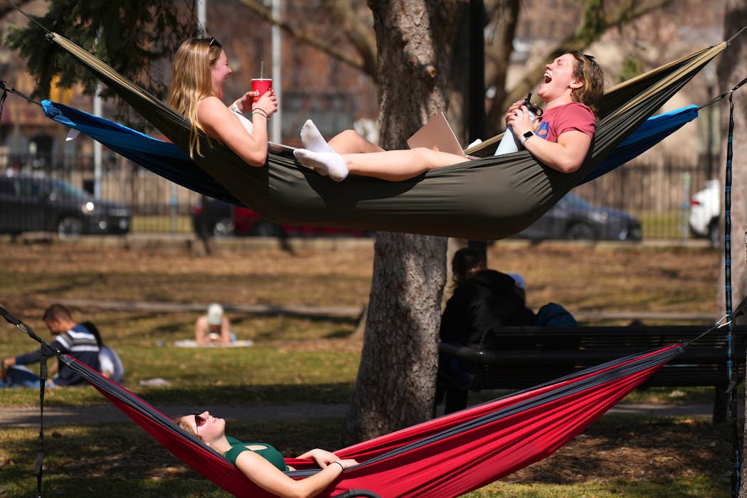 Freshmen Ellie Kohlbeck, top left, Emma Chandler, top right, and Paige Borgmeyer lounged in hammocks after class as temperatures climbed into the mid-70s on Tuesday at the University of Minnesota in Minneapolis.