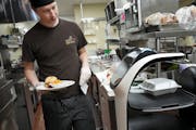 Chef Brennan Danielski loads an order onto a robot, Bella, to bring to the dining room at The Commons on Marice, an assisted-living center in Eagan.