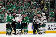 Dallas Stars' Max Domi, center left, and Minnesota Wild's Matt Dumba, center right, both being held by officials are escorted to the penalty boxes aft