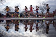 Girls in the 1,600-meter race cast an image on rain water at the Hamline Elite Meet.