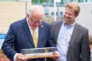 Gov. Tim Walz is presented with an old lead pipe in a glass box by Paul Austin, executive director of Conservation Minnesota, after a bill signing cer