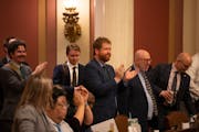 Rep. Zack Stephenson, DFL-Coon Rapids, center, applauded with other members after the 73-57 passage of the bill he authored to legalize recreational m