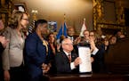 Gov. Tim Walz holds up a just-signed gun control bill on May 19 at the State Capitol in St. Paul. The sweeping public safety bill includes two gun mea