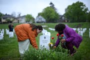 Maude McQuarrie, left, and Amber Martin lay flowers by George Floyd’s gravestone at the “Say Their Names” cemetery May 25, 2022 in Minneapolis.