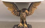 Eagles are a powerful symbol in American designs, from the Great Seal to everyday decorative arts. A carved eagle holds up this table’s faux marble 