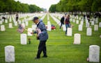 Volunteers with Flags for Fort Snelling place American flags by each headstone on the eve of Memorial Day at Fort Snelling National Cemetery in 2021.