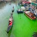 A bright patch of green is seen in the Grand Canal along an embankment lined with restaurants, in Venice, Italy, Sunday, May 28, 2023.